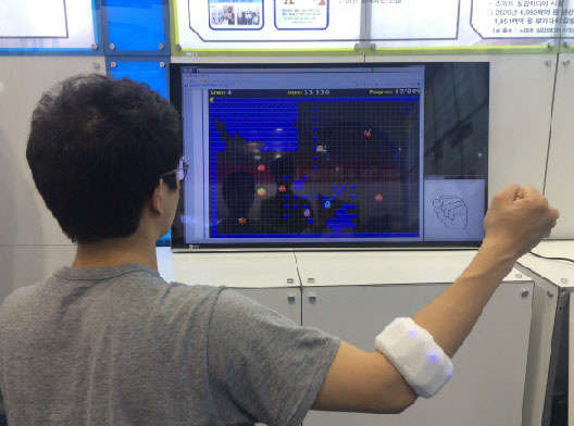 피부 근전도 센서를 착용한 실험자가 손 동작으로 게임을 제어하고 있다. 사진=실감교류인체감응솔루션연구단 제공